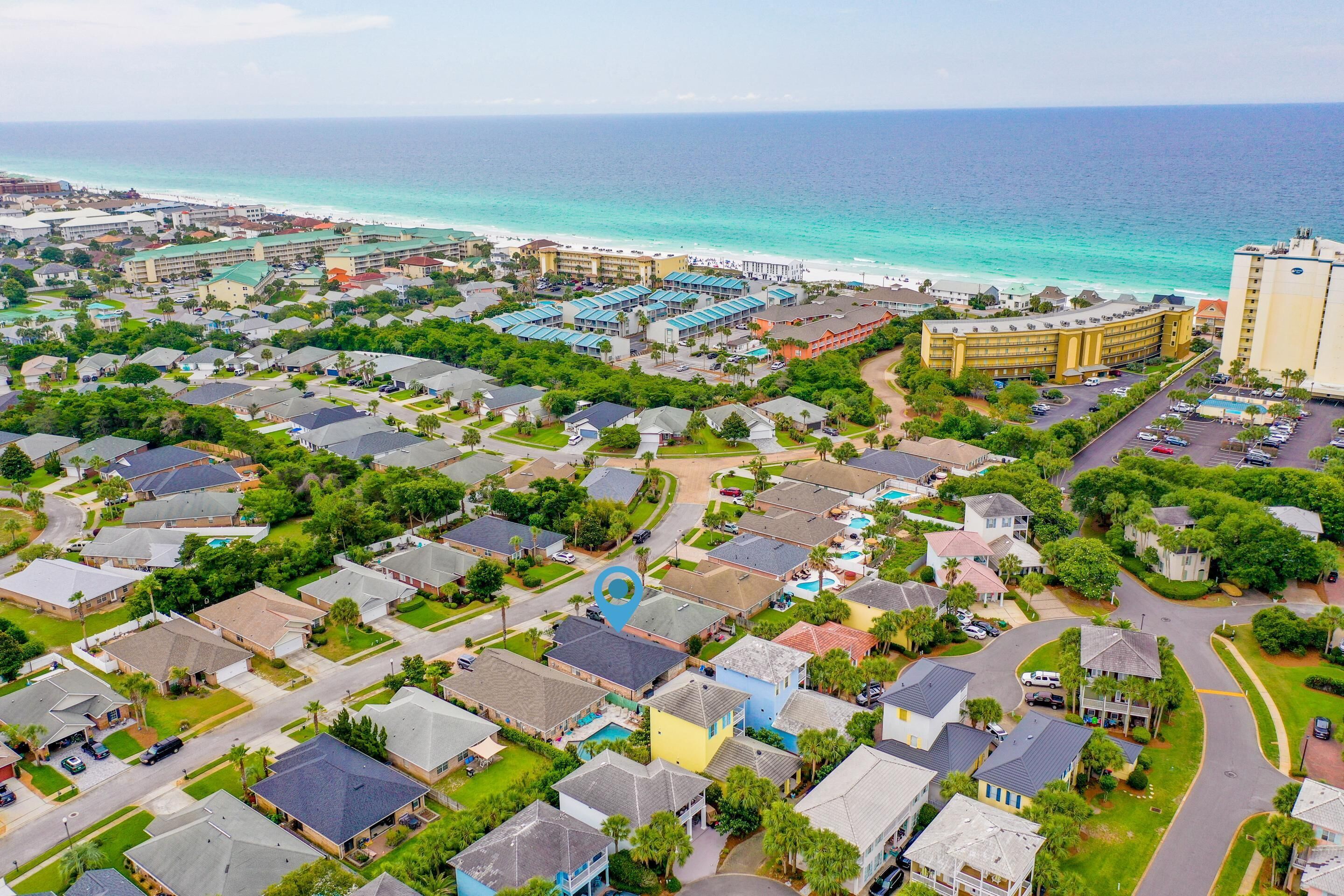 An aerial view of a coastal residential area with houses, a hotel, and a beach.
