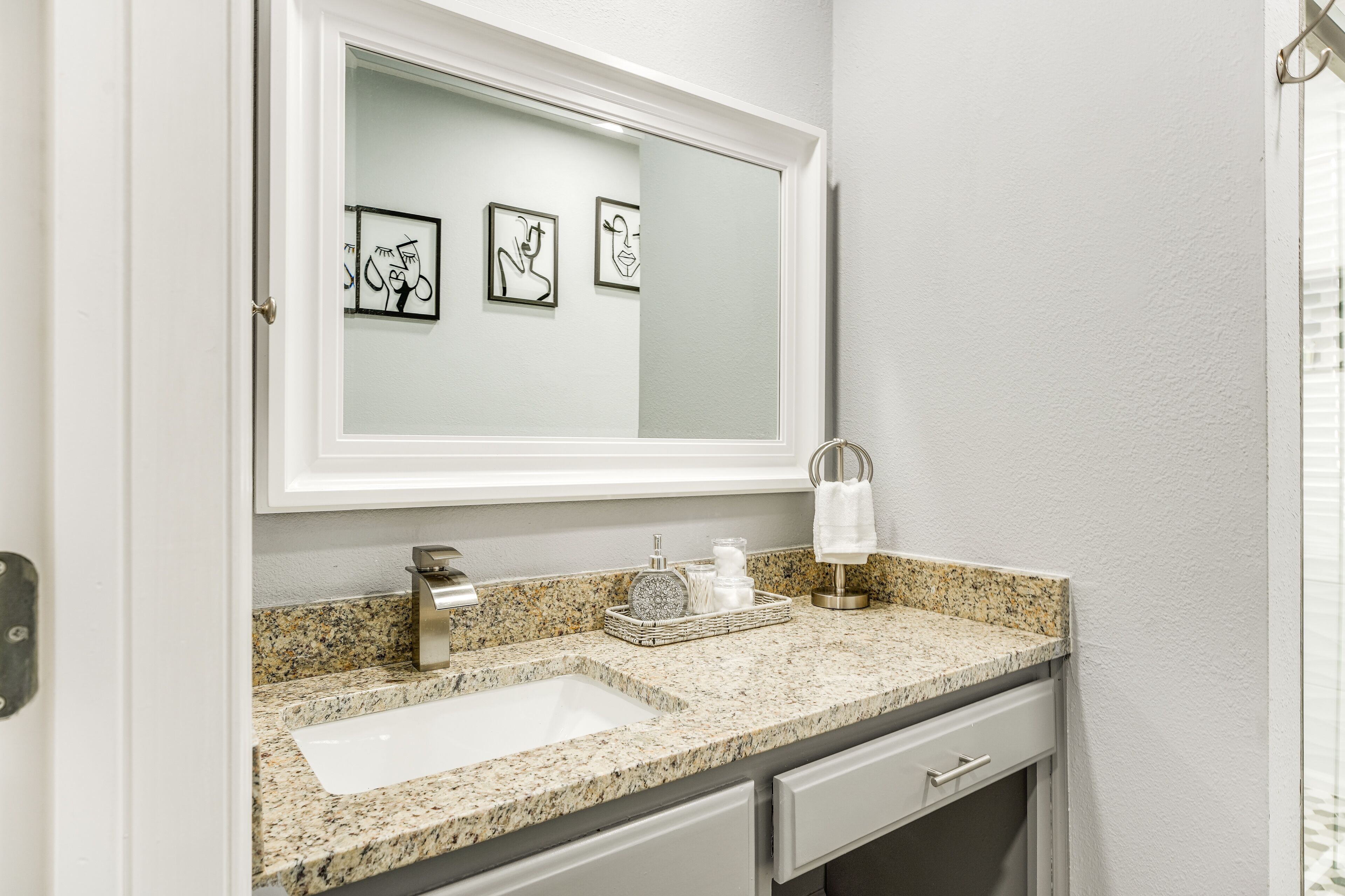 Un bagno con un lavandino bianco, uno specchio e tre quadri appesi al muro.
