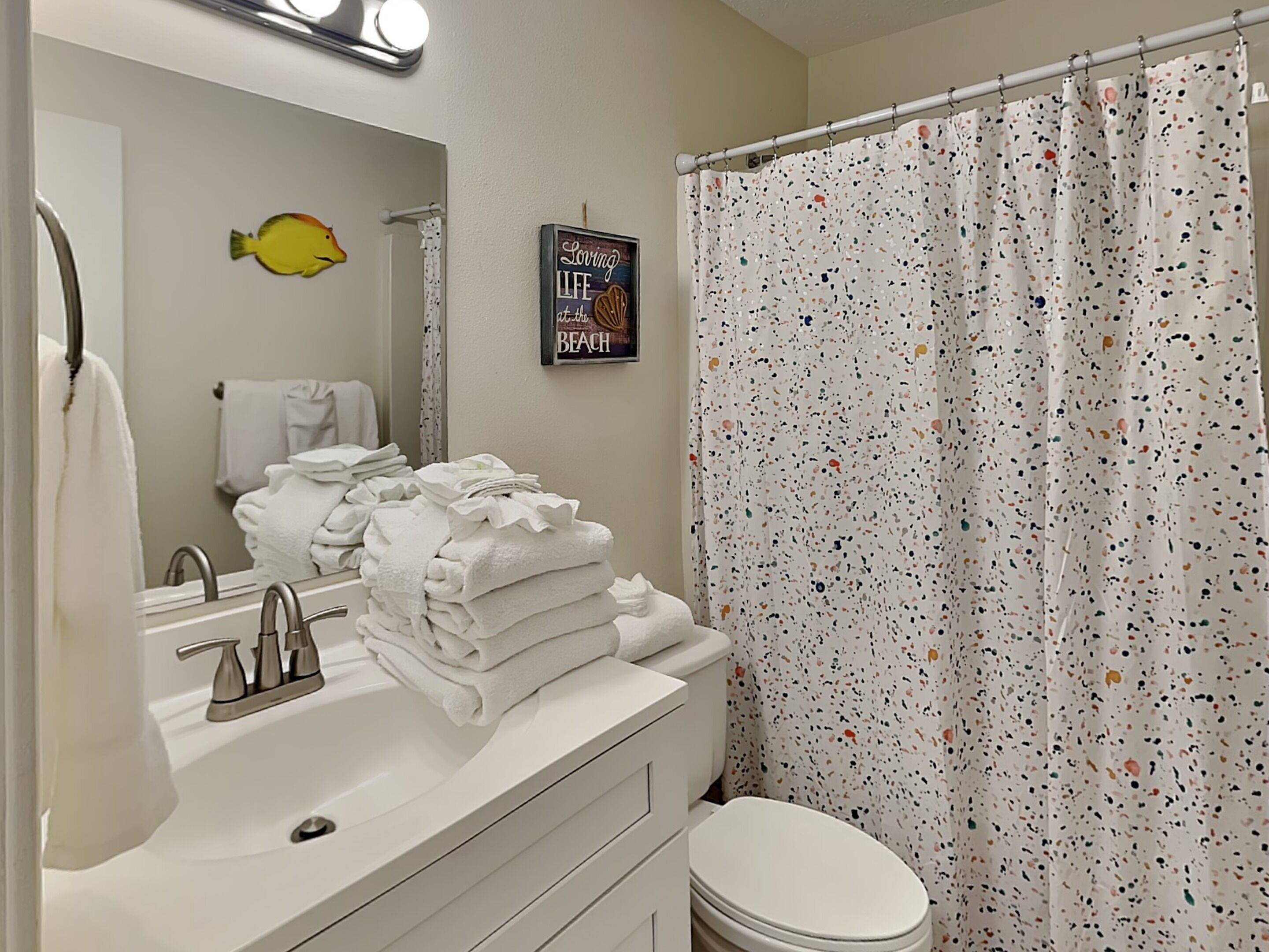 A bathroom with a sink, mirror, and a shower curtain.