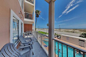 A balcony with lounge chairs, a pool, and a view of the beach. - Grand Beach Resort #311 by Southern Vacation Rentals (Gulf Shores)