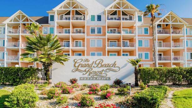 Een meerhoog gebouw met balkons en een bord waarop staat: The Grand Beach Resort Condominium.