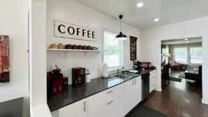 Una cocina moderna con estación de café, armarios blancos y encimera negra.