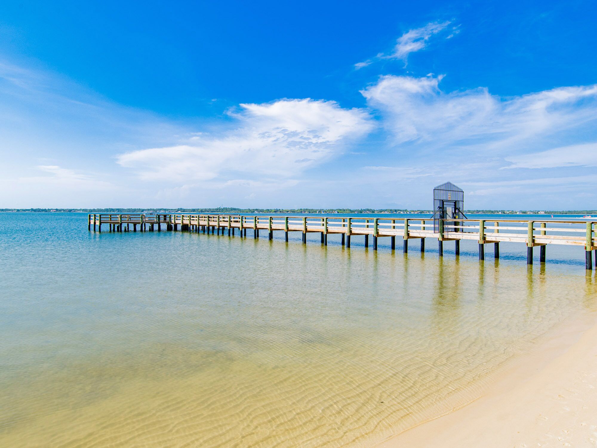 A pier extending into calm waters with a clear sky.