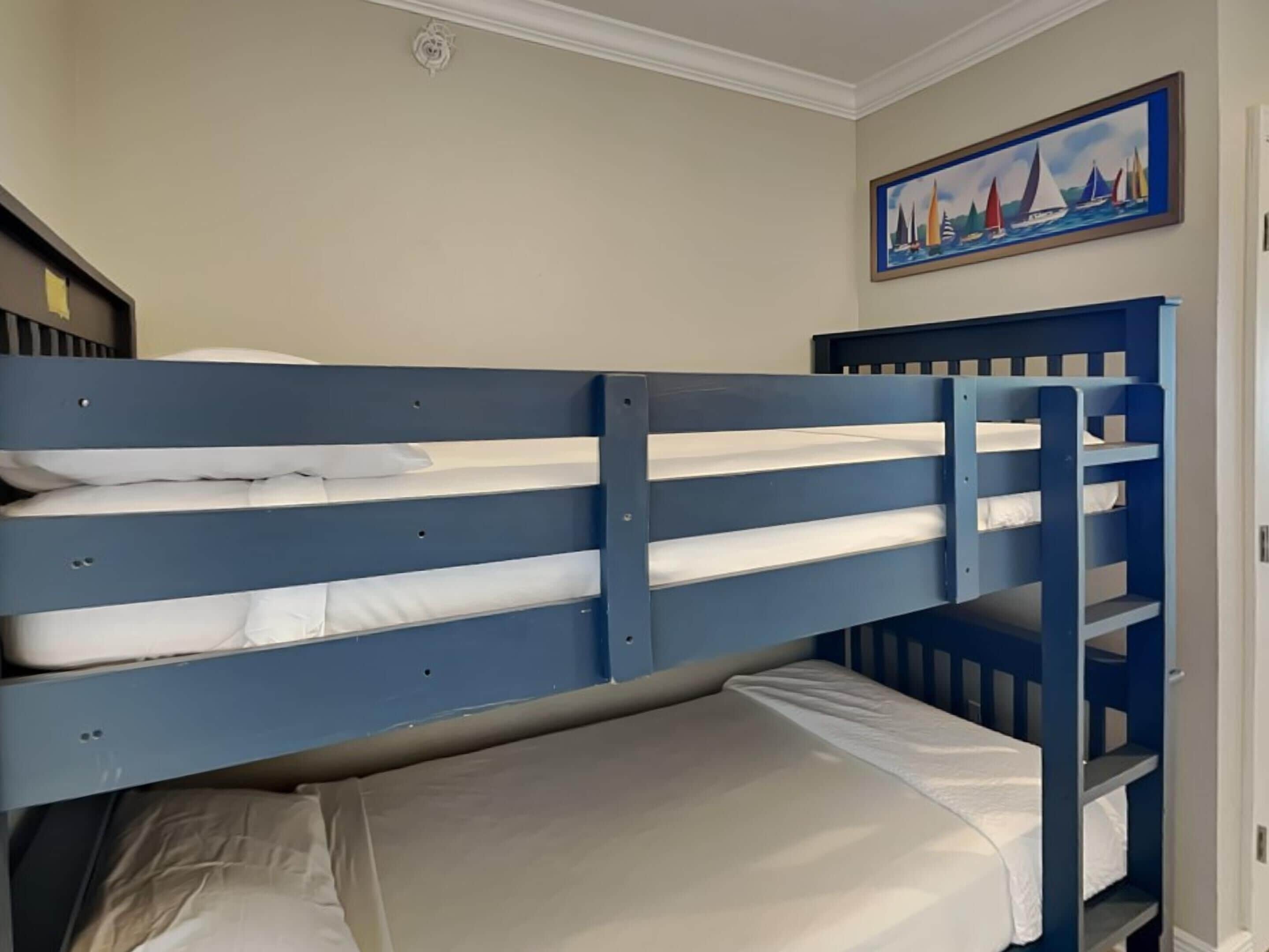Habitación con literas y un cuadro de veleros en la pared.