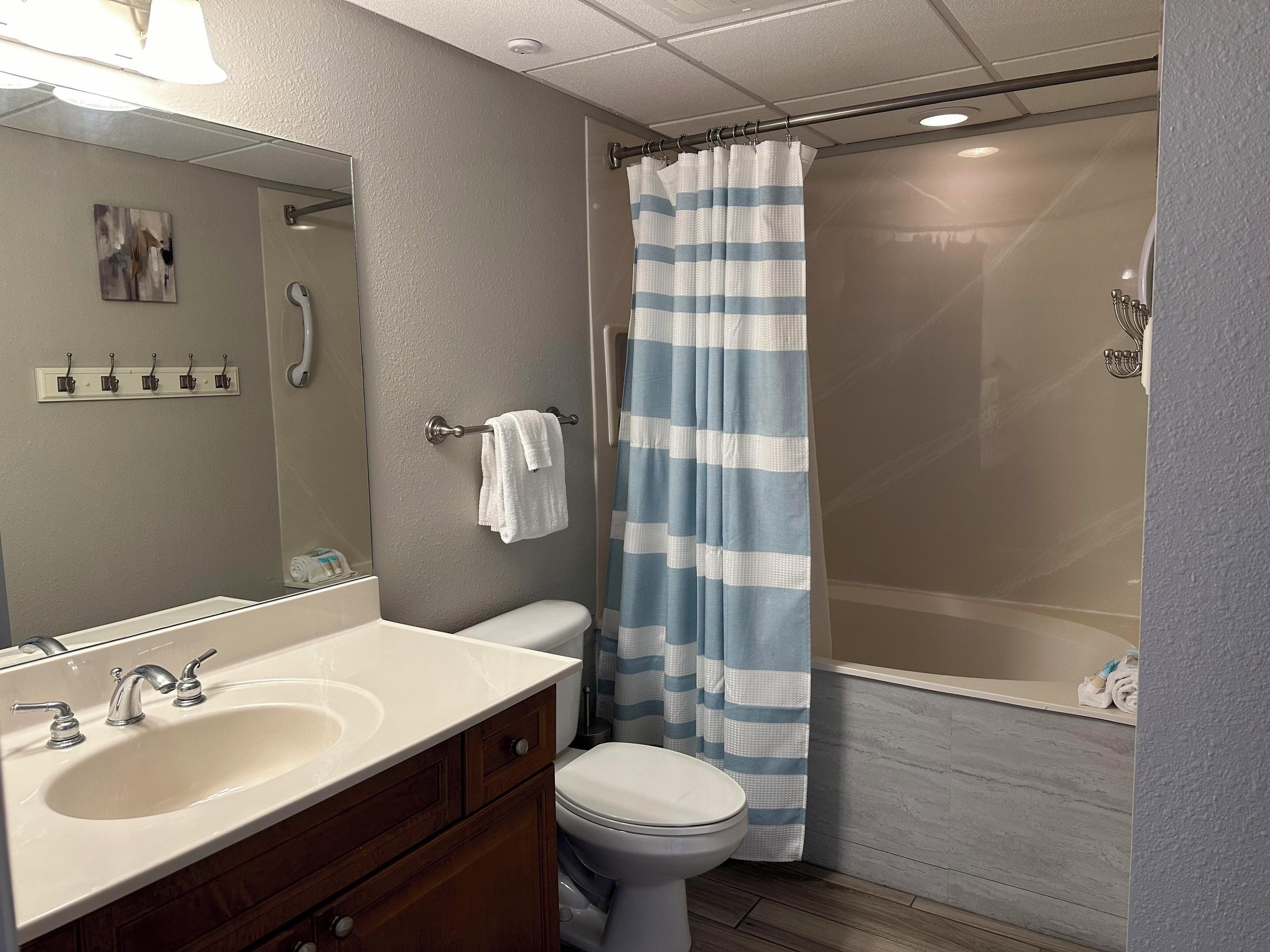 A bathroom with a white sink, a toilet, a shower curtain, and a mirror.