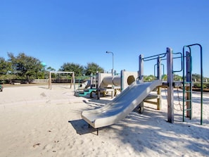 A playground with a slide, climbing structures, and a sand area. - The Beach Club - Doral #701 by Southern Vacation Rentals (Gulf Shores)