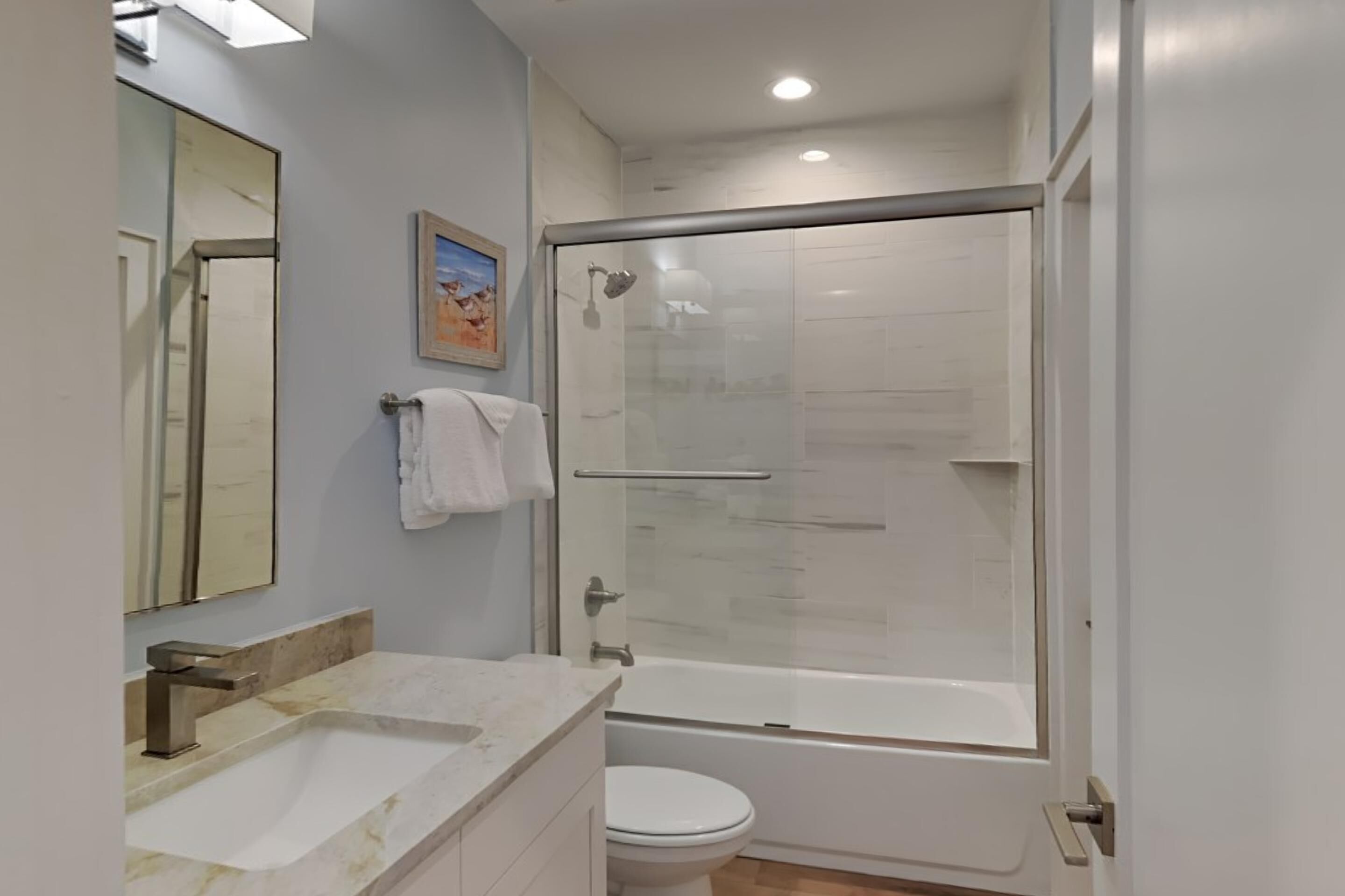 A modern bathroom with a glass-enclosed shower, a white toilet, and a marble sink.