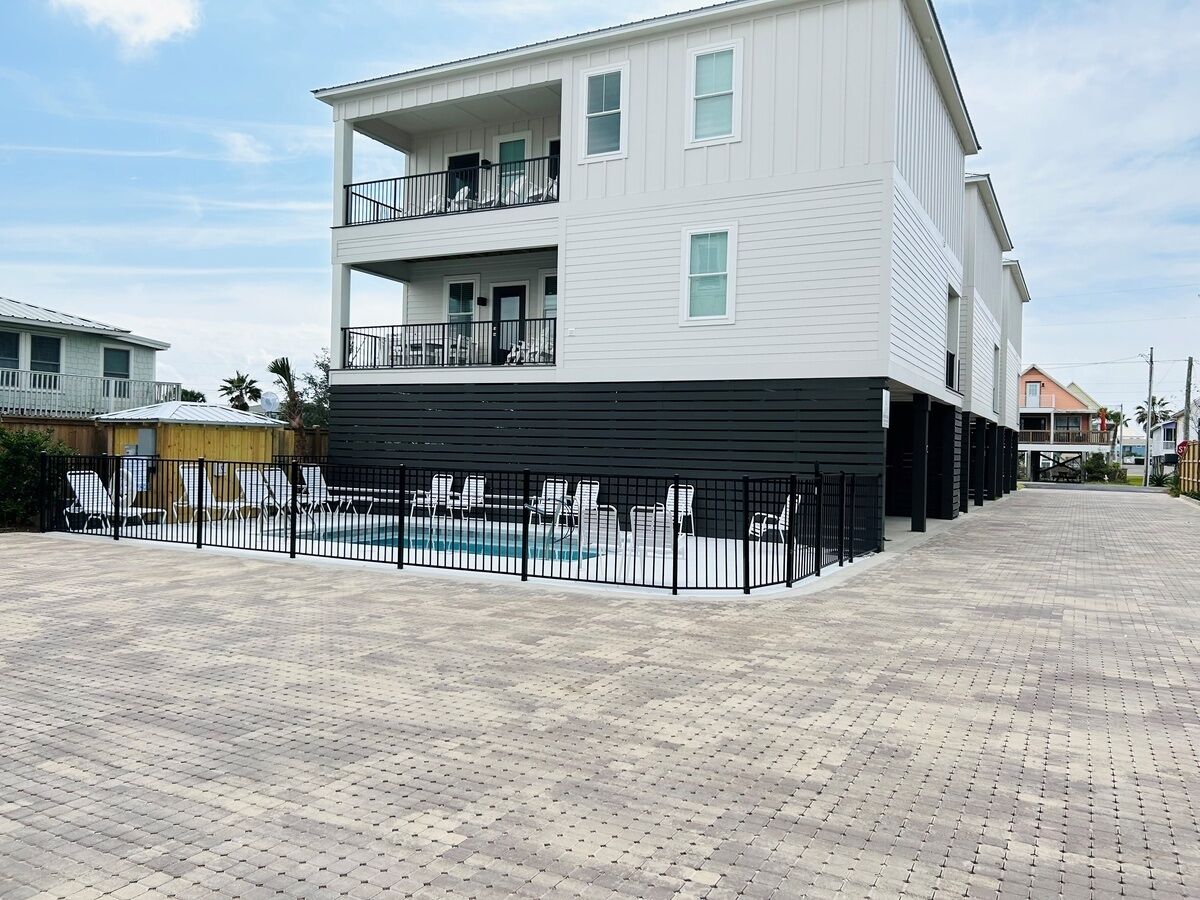 A two-story building with a swimming pool and a fenced patio area.