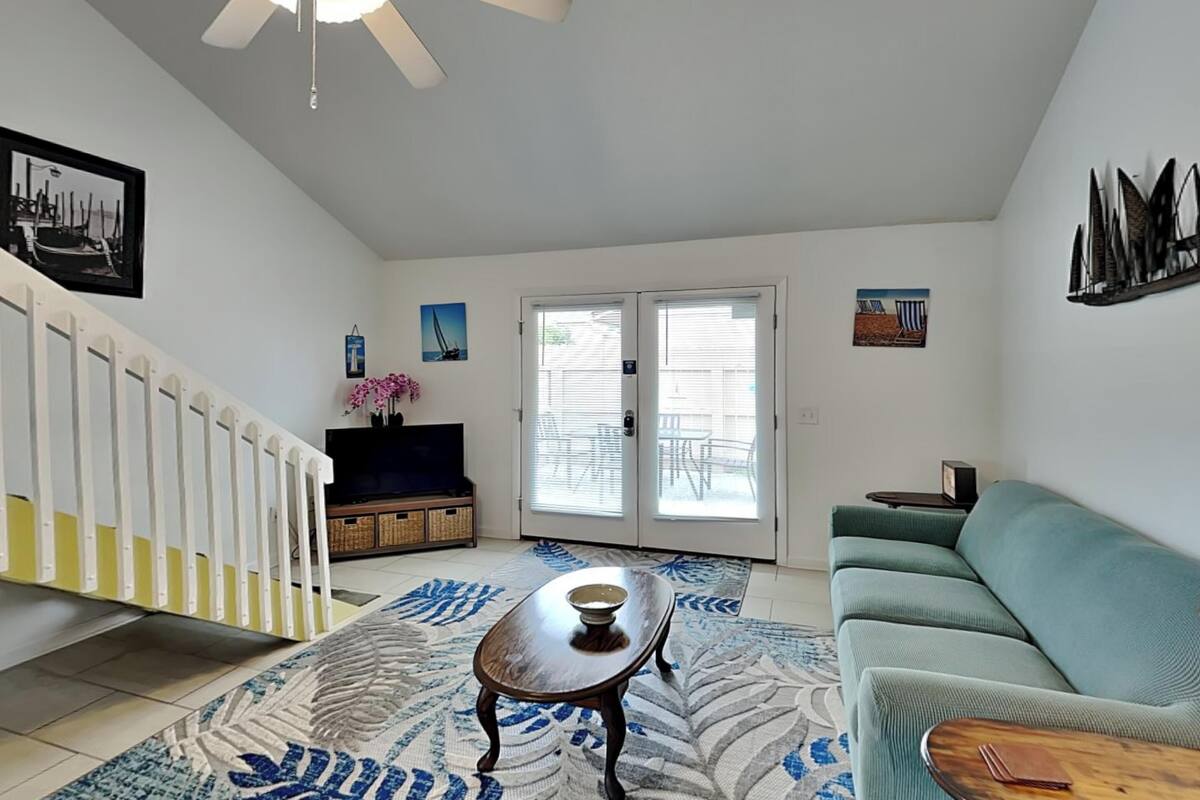 A spacious living room with a sofa, a coffee table, a TV, and a staircase.