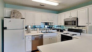 Une cuisine moderne avec des meubles blancs, des appareils en acier inoxydable et un plancher en bois.