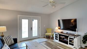 A living room with a sofa, coffee table, TV, and a ceiling fan.