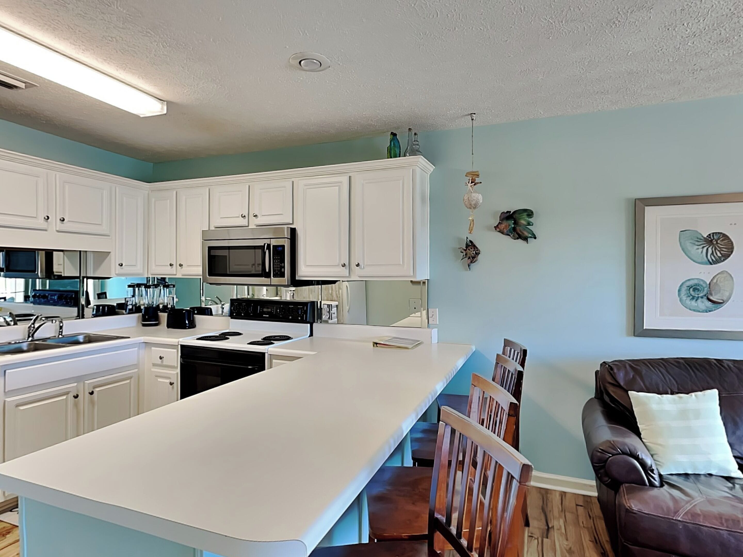A modern kitchen with white cabinets, a large island, and stainless steel appliances.