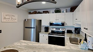 Una cocina moderna con armarios blancos, electrodomésticos de acero inoxidable y encimera de mármol.