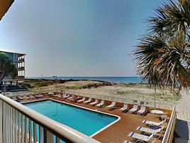 A poolside area with lounge chairs and a view of the beach.