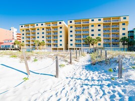 Un hôtel situé en bord de mer, doté de nombreux balcons et donnant sur une plage de sable.