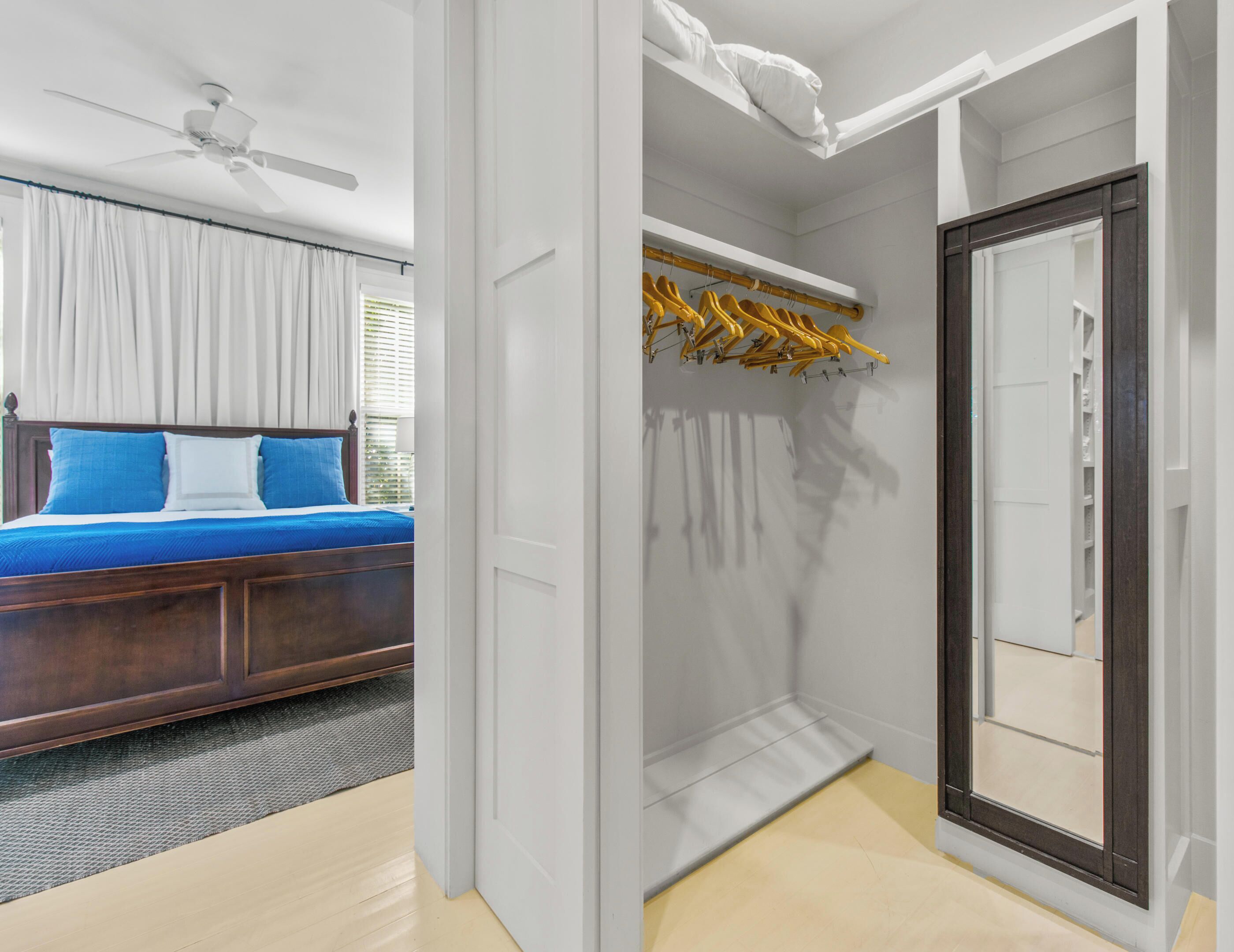 Une chambre à coucher avec un lit, un ventilateur de plafond et une fenêtre avec des rideaux.
