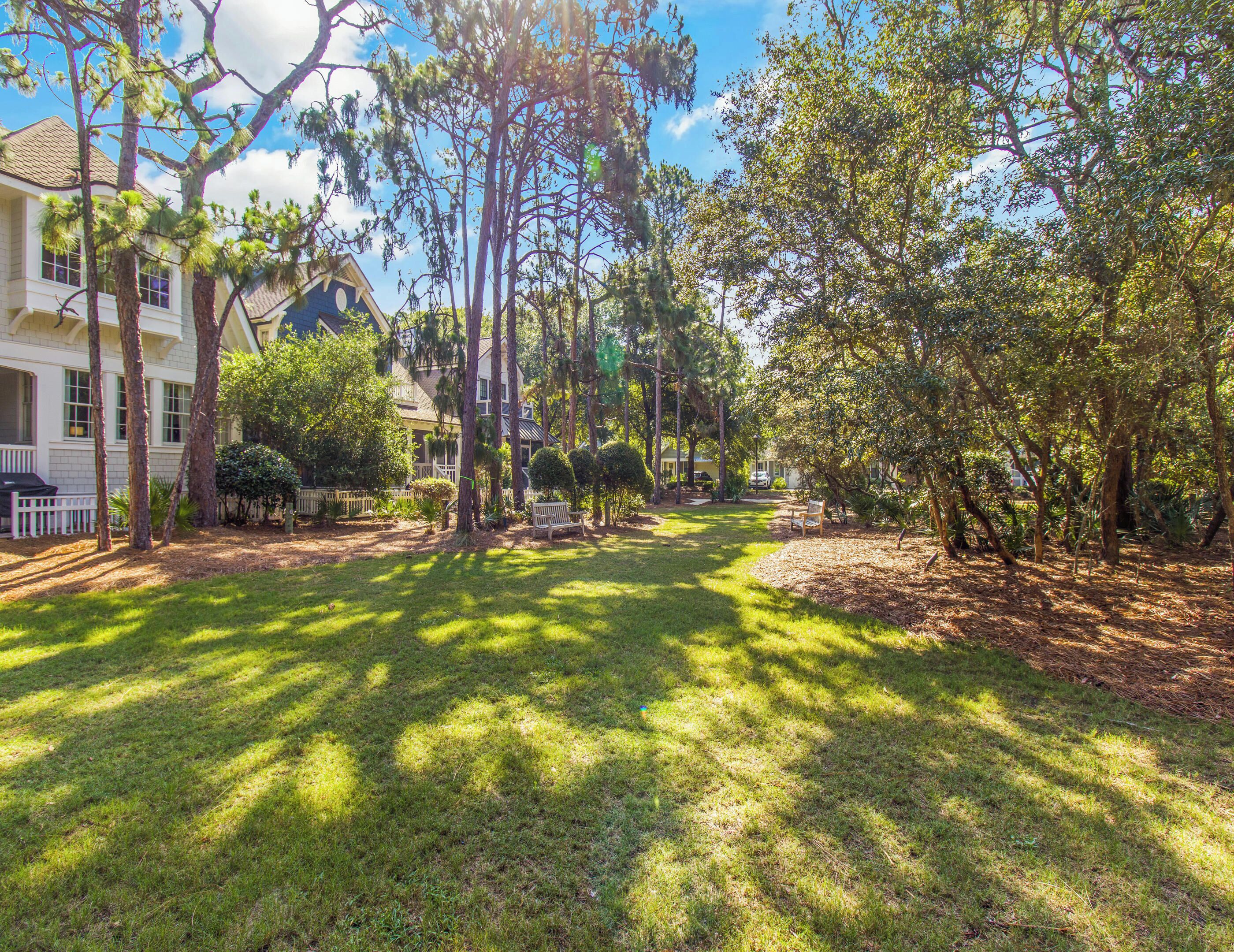 A residential area with a well-maintained lawn, trees, and a house with a porch.