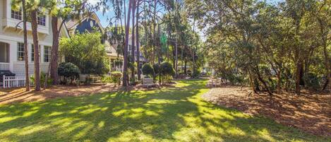 A residential area with a well-maintained lawn, trees, and a house with a porch.