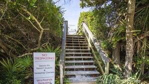 A wooden staircase surrounded by dense foliage with a sign indicating 'NO TRESPASSING' for Destin RV Resort Guests and Seaspray Owners. - Seaspray by Southern Vacation Rentals (Miramar Beach)