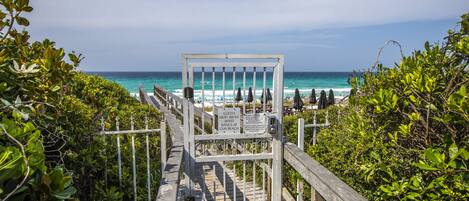 A wooden boardwalk leading to a beach with a sign indicating guests must wear a wristband.
