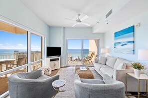 Enjoy ocean views from the large window in this stylish living room, featuring a sofa, armchairs, coffee table, and flat-screen TV.