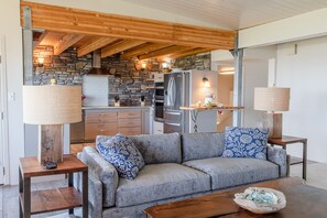 Relax in this inviting living space with a comfortable sofa, wooden coffee table, and kitchen area.