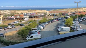 A parking lot with cars and a view of a beach and buildings in the distance. - Seignosse Ocean, beautiful renovated apartment OCEAN VIEW 150m from the beach, ideal family (SEIGNOSSE)