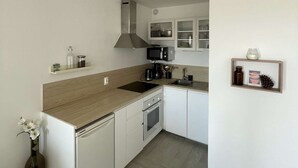 A modern kitchen with white cabinets, a wooden countertop, a stove, and a microwave. - Seignosse Ocean, beautiful renovated apartment OCEAN VIEW 150m from the beach, ideal family (SEIGNOSSE)