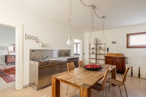 A modern kitchen with a wooden dining table, chairs, and a fruit bowl.