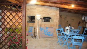A rustic stone interior with a brick oven, blue chairs, and a wooden ceiling. - ROMANTIC PENTHOUSE 7 BEDS (Case Alte)