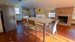 A dining area with a table and chairs, a kitchen with a refrigerator and microwave, and a brick fireplace. - ROMANTIC PENTHOUSE 7 BEDS (Case Alte)