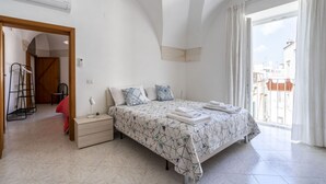 A bedroom with a bed, bedside table, and a view of the outside.