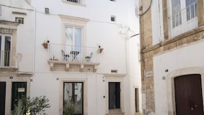 A white building with a balcony, a door, and a window.