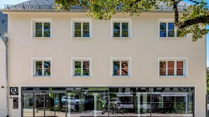 A building with a beige facade, multiple windows, and a glass storefront. - Hotel Das Q Spaichingen (Spaichingen)