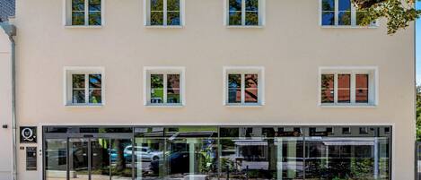Un edificio con fachada color crema, varias ventanas y escaparate de vidrio.