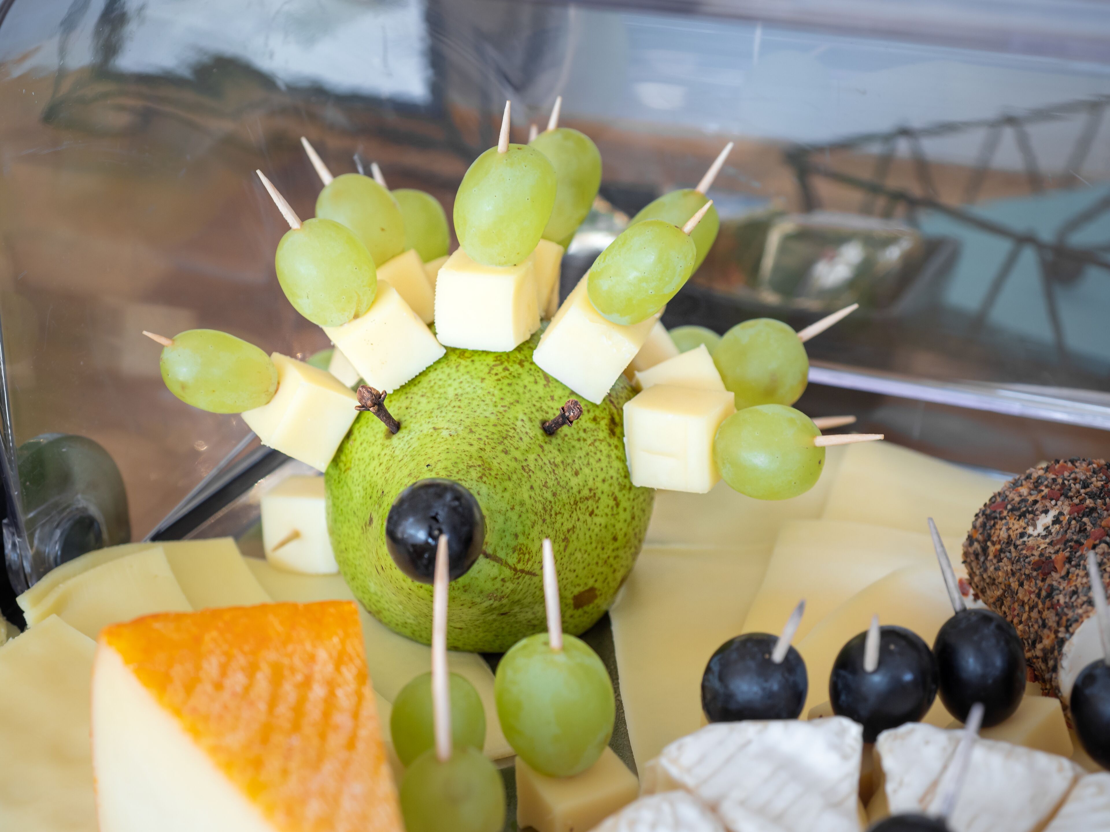 Un vassoio di frutta con uva, formaggio e olive.