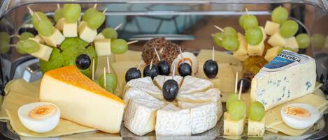 A variety of cheeses, grapes, and olives arranged in a clear plastic container.