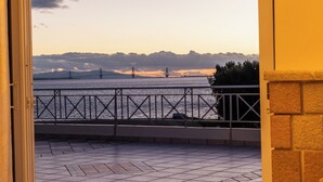 A balcony with a view of a bridge over water, a railing, and a tiled floor.