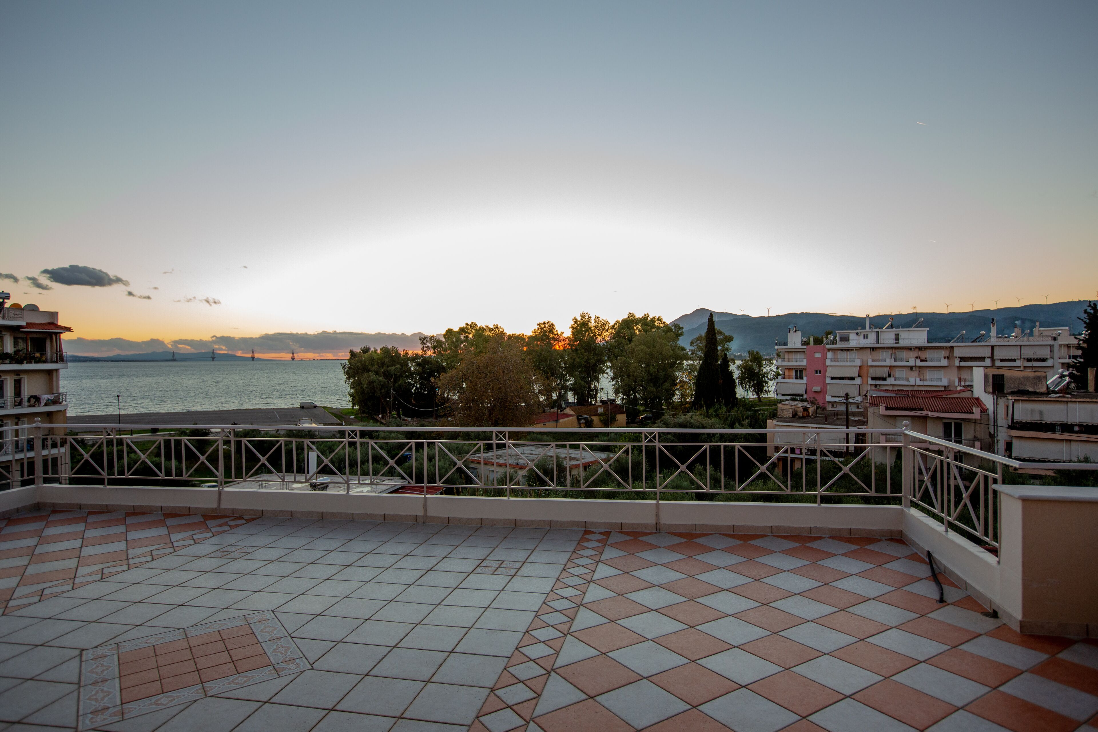 Una terraza con suelo de baldosas y vistas al mar y a las montañas.