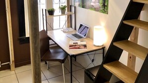Un llit superposat amb un escriptori a sota, un ordinador portàtil, una làmpada i un quadre al mur.