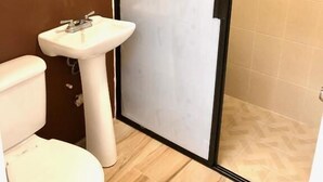 Un bany amb vàter, rentapel i zona de dutxa amb porta corredissa.