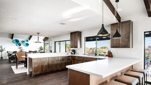 Een moderne keuken met een groot eiland, houten kastjes en hanglampen.