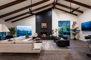A spacious living room with a fireplace, leather sofas, and a large window overlooking a scenic view.