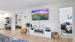 A living room with a fireplace, a flat-screen TV, and a bookshelf. - Waterfront Cozy Cove Retreat - LOTO Escape, Remodeled Comfort, Close to the Fun (Lake Ozark)