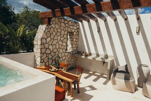 Une terrasse avec un mur en pierre, une table en bois, des chaises, un jacuzzi et un évier encastré.