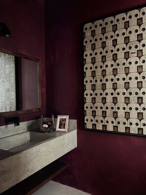 Une salle de bain avec un lavabo en marbre, un miroir et un panneau décoratif mural.