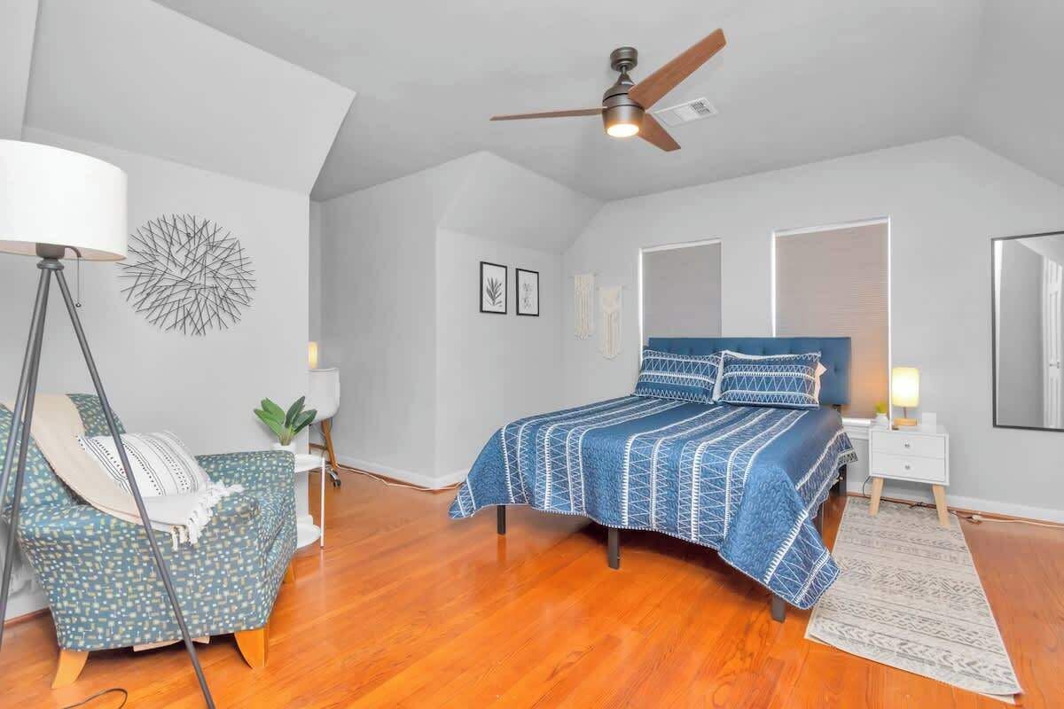 A bedroom with a bed, a chair, a floor lamp, and a ceiling fan.