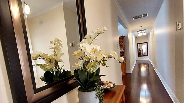 A hallway with a large mirror, a potted orchid, and a decorative bowl on a wooden console table. - Home with easy access to CBD: Magill (Magill)