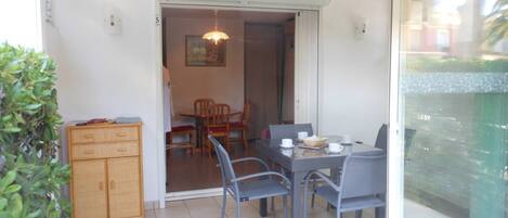 A dining area with a table and chairs, a wooden cabinet, and a glass door leading to another room.