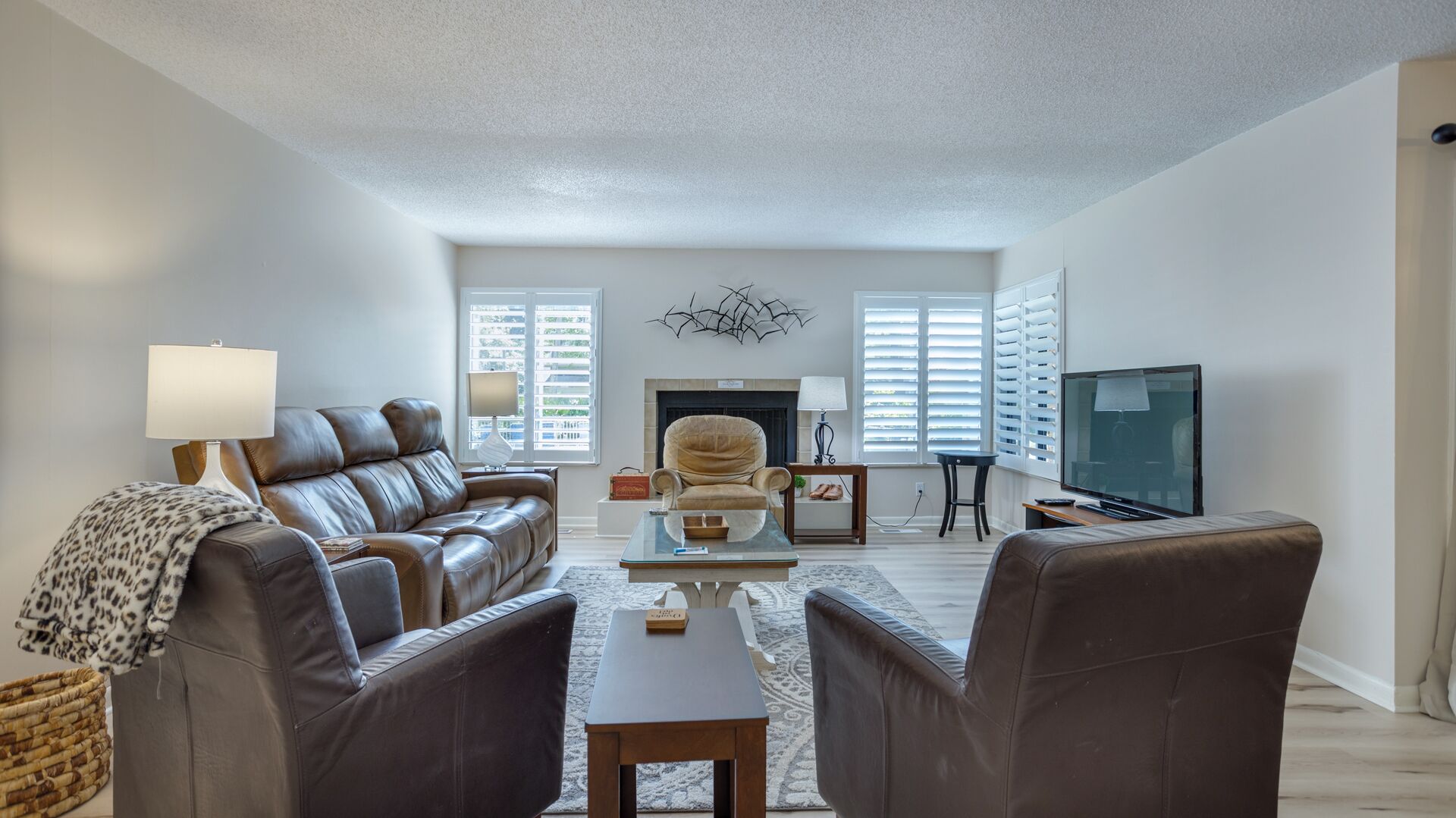 A modern living room with a leather sofa, armchairs, a coffee table, and a fireplace.